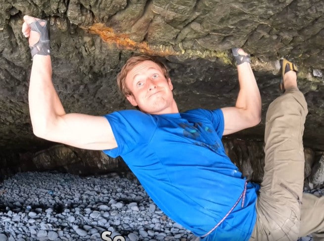 Climber using crack gloves on a vertical sandstone crack climb in Indian Creek, Utah, demonstrating proper jamming techniques. 