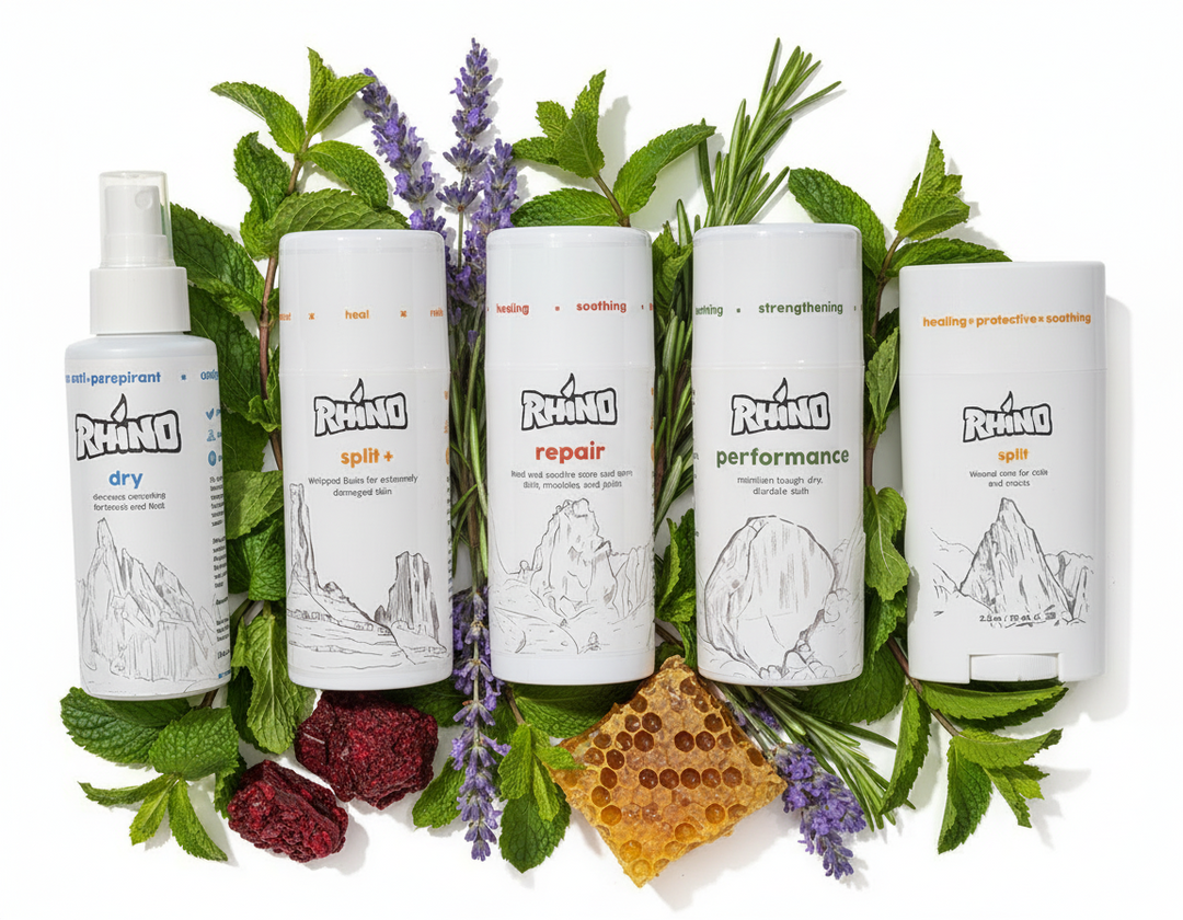Five Rhino care product bottles surrounded by herbs and natural elements on a white background