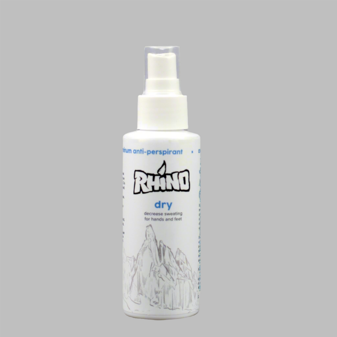 A Rhino Dry spray bottle displayed on a smooth gray background. The sleek design of the bottle contrasts against the neutral gray surface, emphasizing the product's simplicity and effectiveness. The clean, minimalist setting highlights the bottle's labeling and branding, making it stand out as a reliable non-aluminum anti-perspirant for active individuals seeking to reduce sweating in hands and feet. The image conveys a sense of professionalism and practicality, ideal for showcasing the product's benefits i