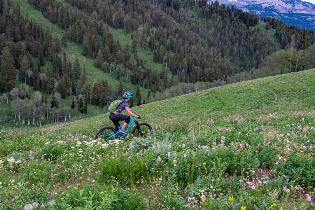 Mountain biker crossing a meadow — Rhino skin care for MTB riders.