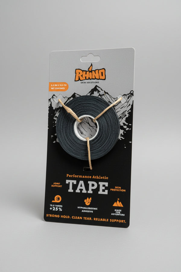 A roll of Rhino brand athletic tape in black, mounted on a retail backing card, displayed on a wooden table with storage bins in the background.