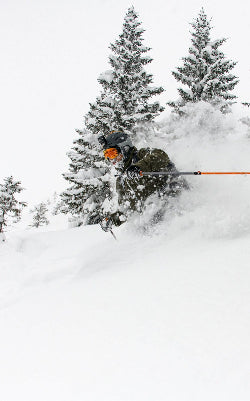 Person skiing through deep snow in a forest with trees covered in snow.
