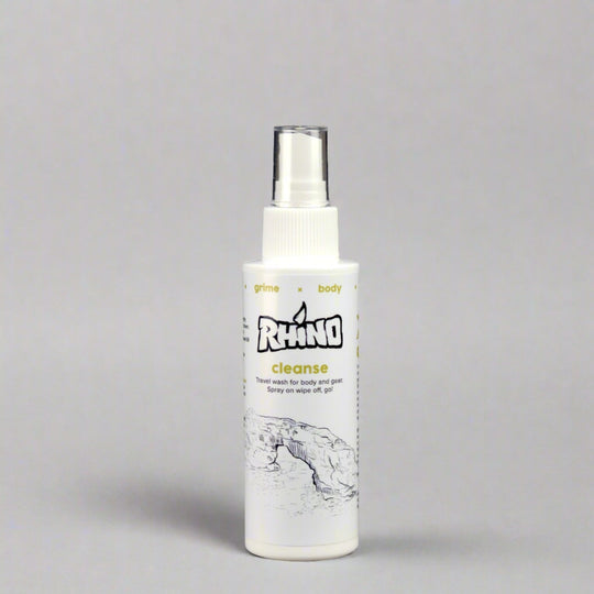 The Rhino Cleanse Spray bottle is placed on a smooth gray background with a soft shadow cast beneath it. The clean, minimalist setting emphasizes the sleek design of the bottle and the clarity of the label, which highlights its antifungal and antibacterial properties. The shadow adds depth to the image, making the product stand out, perfect for showcasing the spray’s effectiveness as a post-workout and adventure gear cleaner.